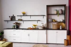 A Scandinavian-style kitchen interior in white and brown tones, featuring a balanced mix of open shelving vs. cabinet with shelves.