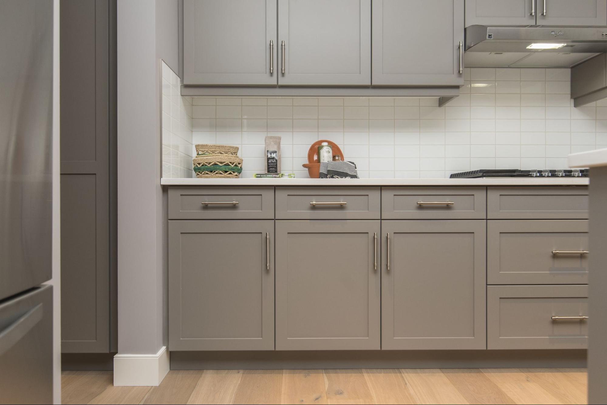 A modern style kitchen featuring gray-painted Shaker-style kitchen cabinets with golden handles.