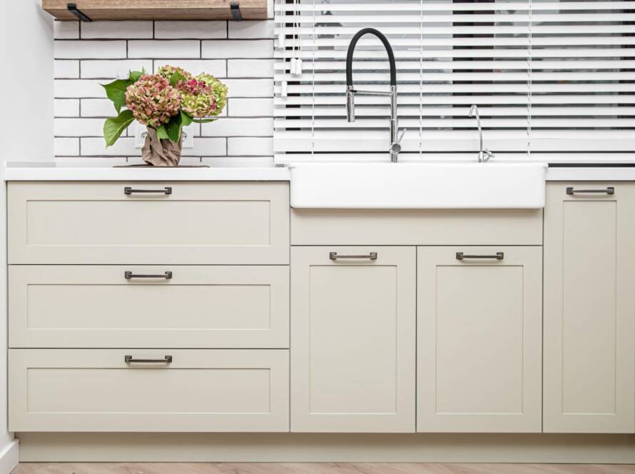 Off-white wooden cabinets in a white kitchen.