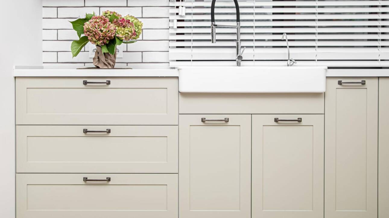 Minimalist washbasin setup with greige Shaker-style cabinets and a clean white countertop.