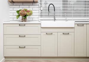 Minimalist washbasin setup with greige Shaker-style cabinets and a clean white countertop.