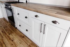 A closeup of Shaker-style cabinets in gray paint with steel handles.