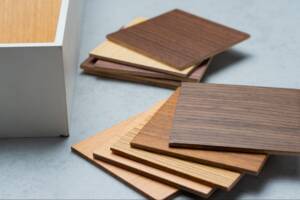 Some samples of wood for cabinet wood stacked on a table.