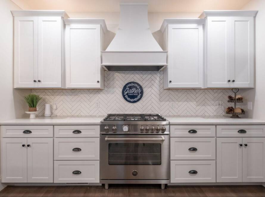 Modern white kitchen cabinets with gas stove and wall-mounted rangehood.
