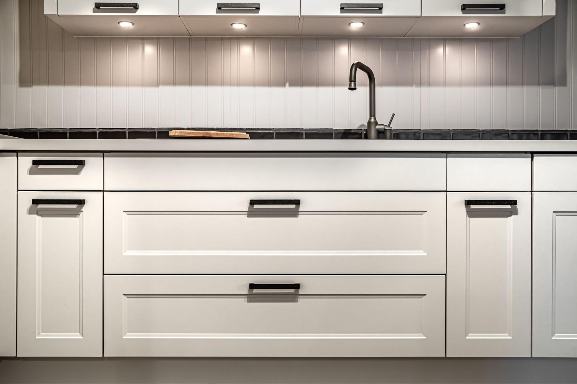 Shaker-style cabinets painted in white with black pulls and knobs.